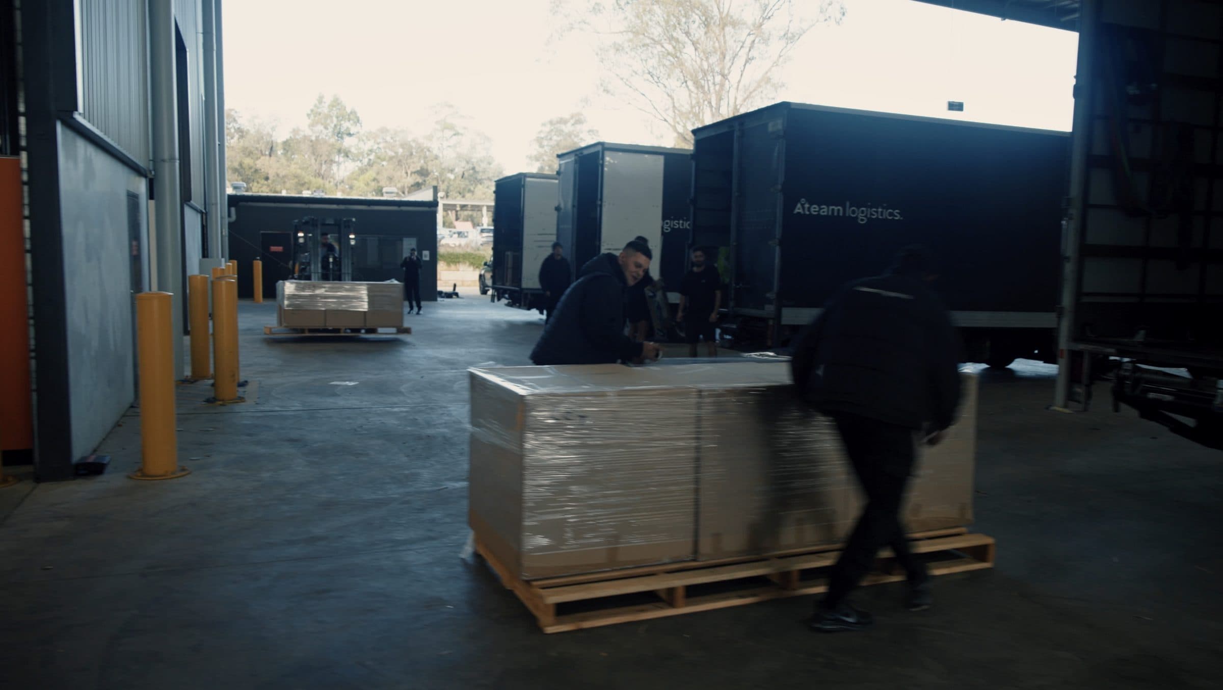 Ateam Logistics handlers carrying an ornate gold-patterned chaise longue across the warehouse floor towards a waiting truck.