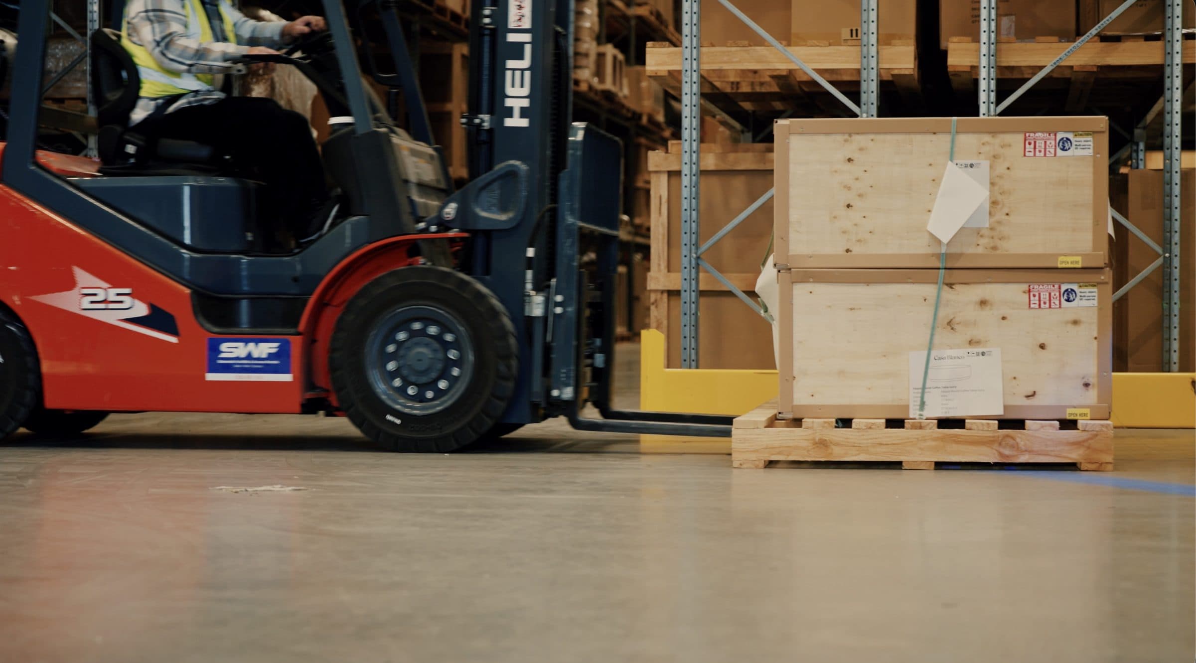 A forklift moving crated stock inside the Ateam Logistics warehouse.
