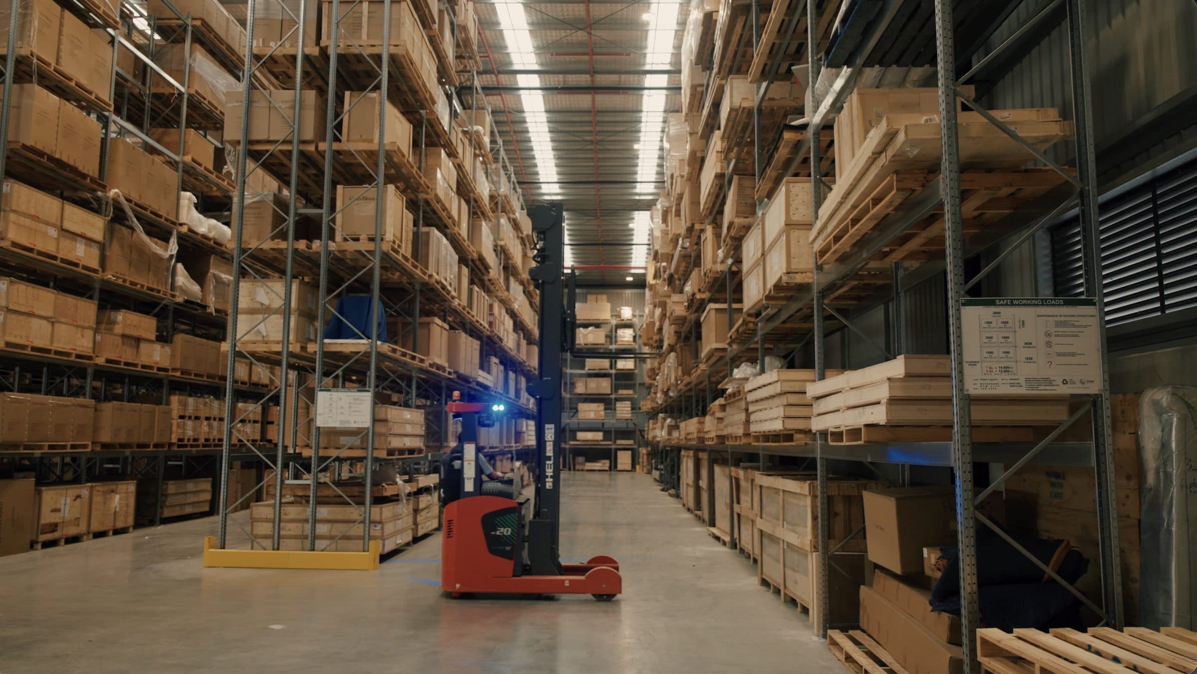A reach truck working an aisle inside the Ateam Logistics facility, racking stacked several levels high on both sides.