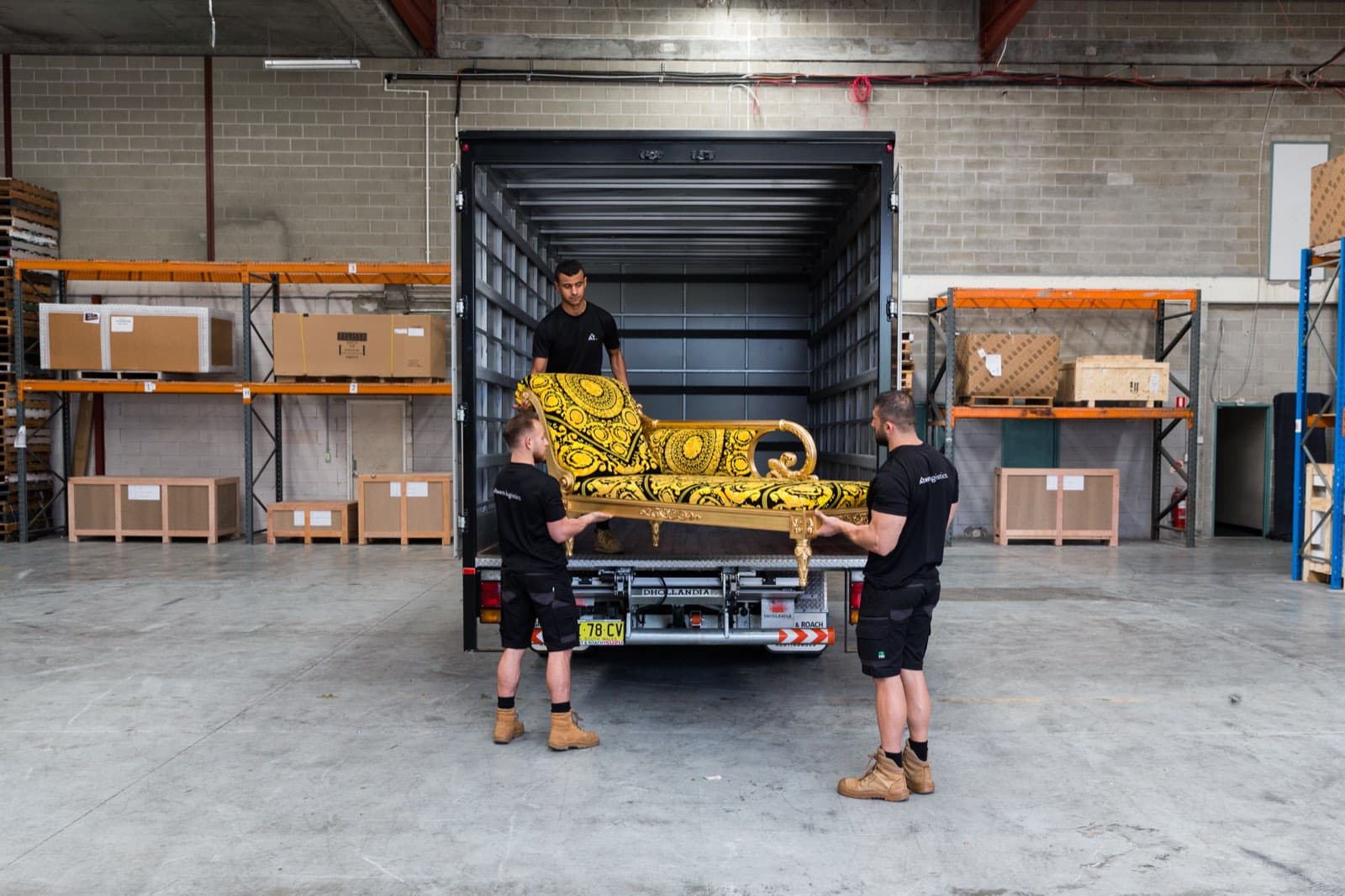 An ornate chaise longue being loaded onto the tailgate of a branded Ateam Logistics truck at the Sydney dock.